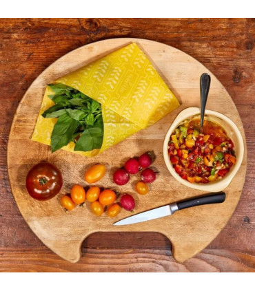 Planche en bois ronde avec salade de multiples tomates et basilic enrobé dans emballage alimentaire